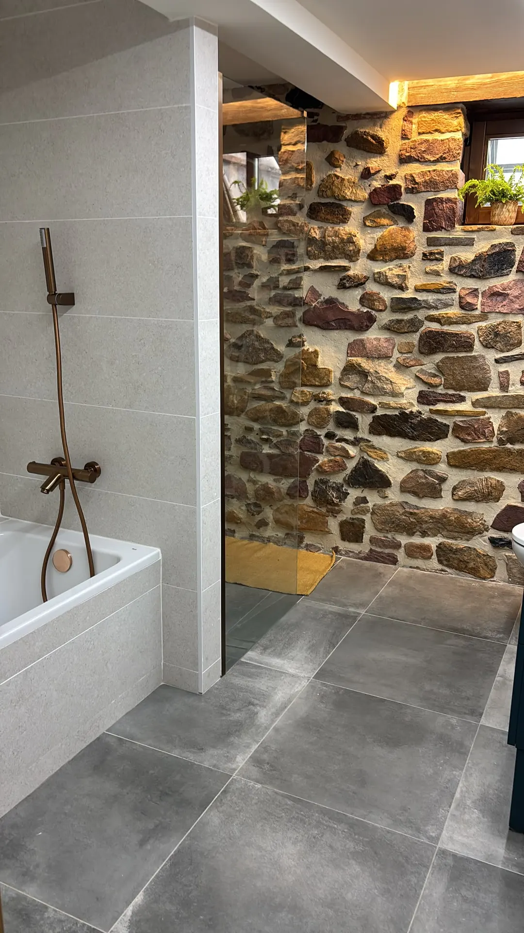 Baño con pared de piedra y lavabo de piedra natural, trabajo de Dos Ambients