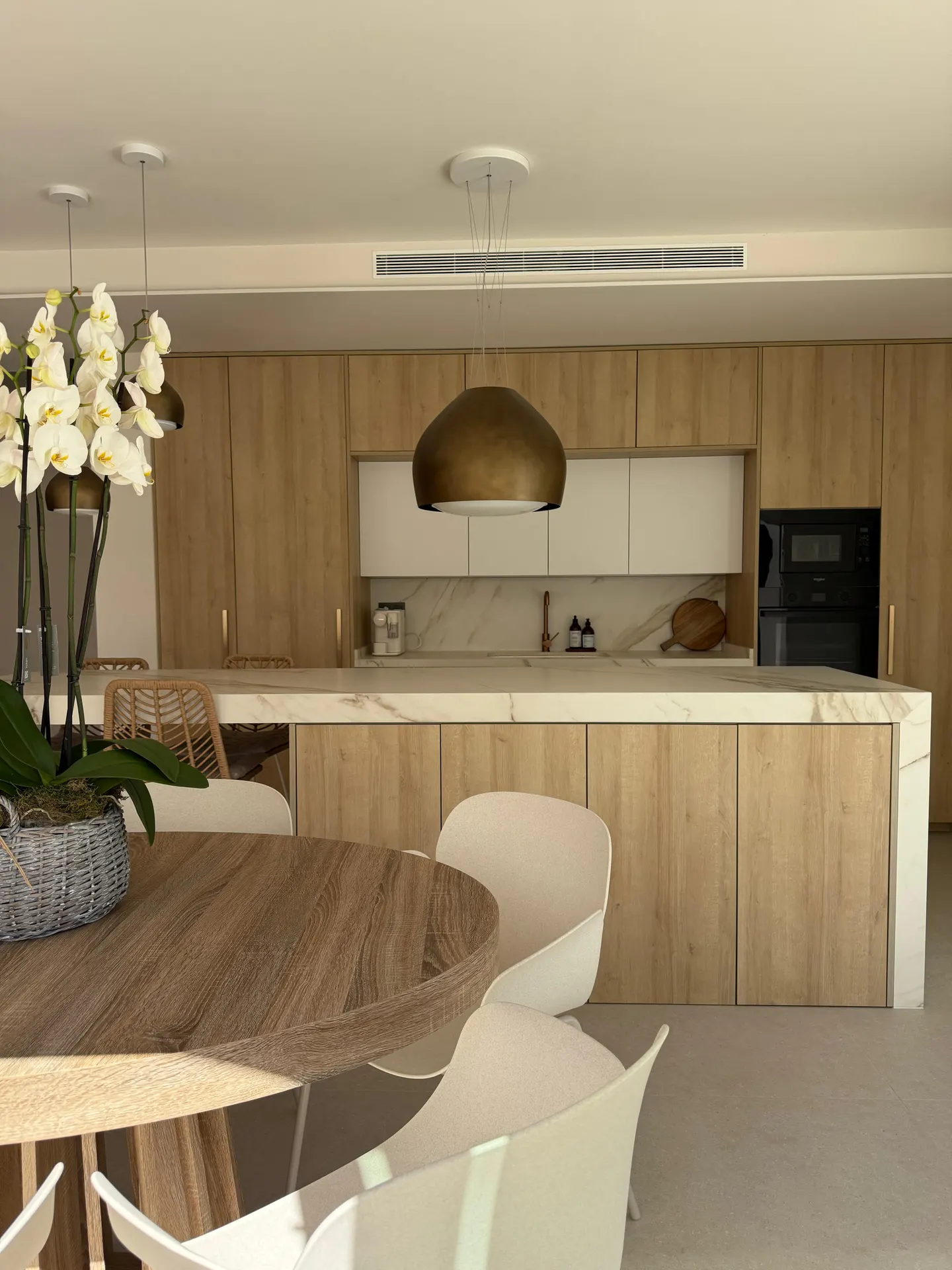 Cocina en madera con isla y encimera efecto mármol, trabajo de Dos Ambients