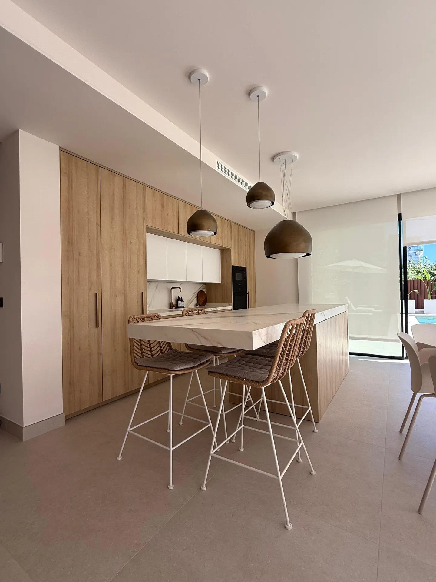Cocina en madera con isla y lámparas colgantes, trabajo de Dos Ambients