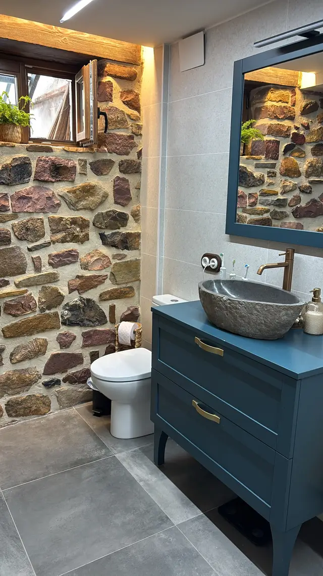 Baño con bañera y pared de piedra, trabajo de Dos Ambients