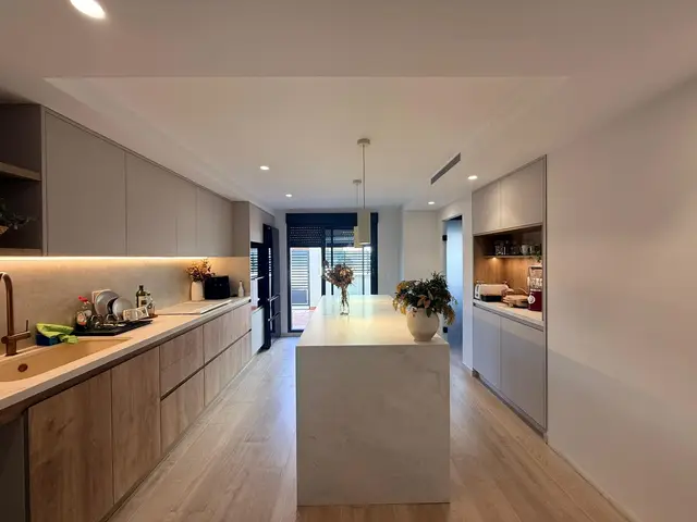 Cocina abierta con isla y frentes de madera, trabajo de Dos Ambients