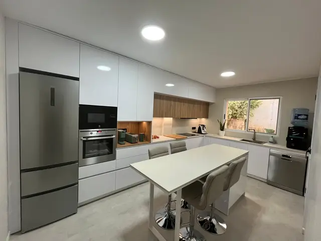 Cocina blanca con isla y electrodomésticos integrados, trabajo de Dos Ambients