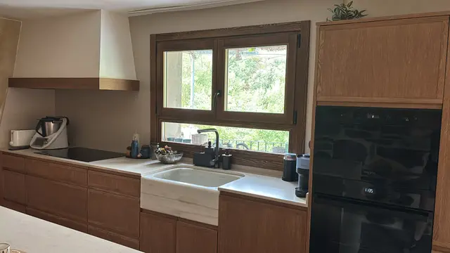 Cocina en madera con campana integrada y ventana, trabajo de Dos Ambients