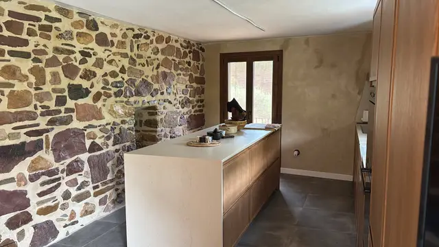 Cocina en madera con fregadero de mármol bajo la ventana, trabajo de Dos Ambients