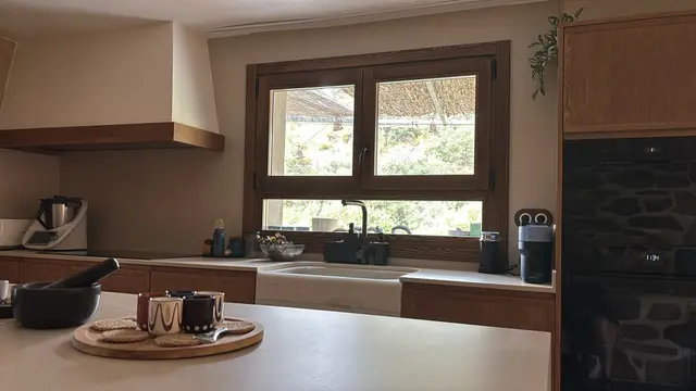 Cocina con isla junto a pared de piedra, trabajo de Dos Ambients