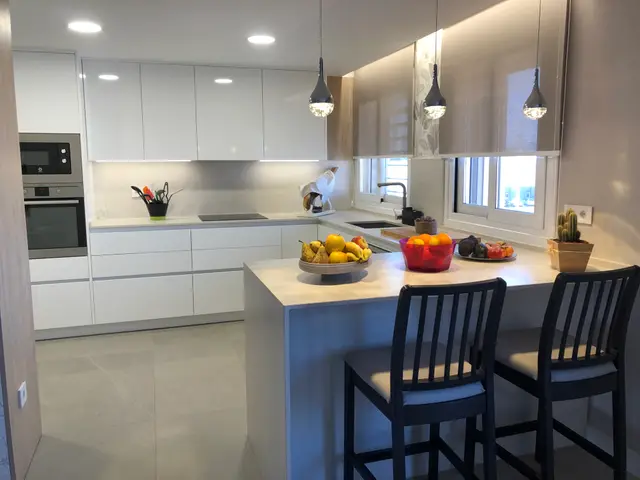 Cocina blanca con península y barra, trabajo de Dos Ambients